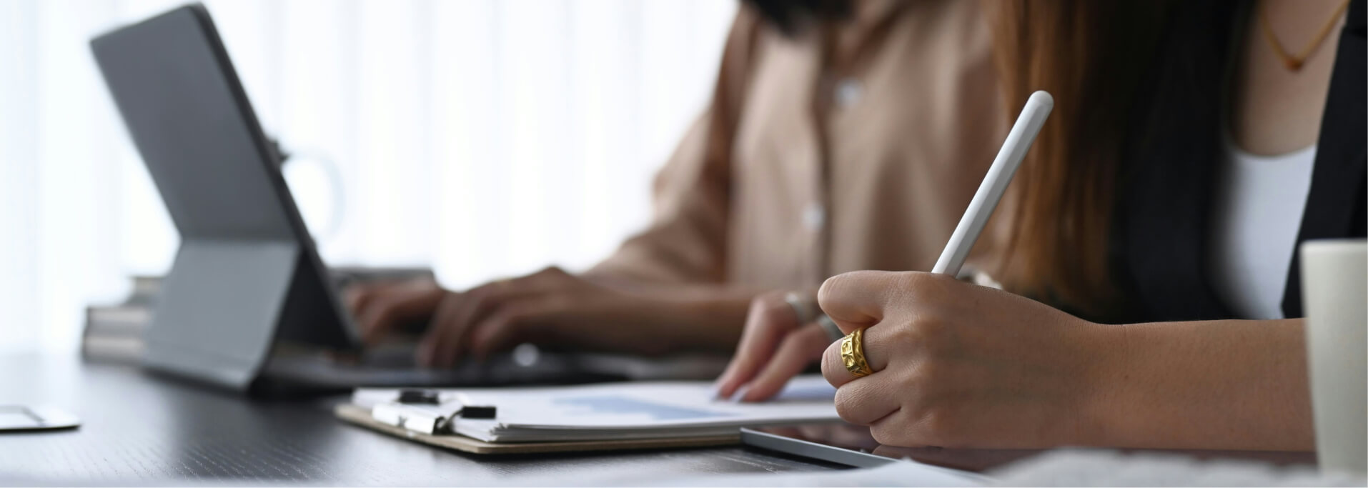Zwei Personen arbeiten gemeinsam an einem Laptop und Dokumenten.